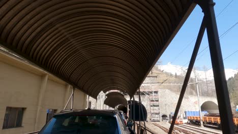 lotschberg car train approaching tunnel through mountain. switzerland