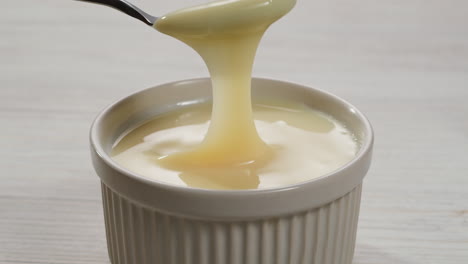 saborosa leche condensada, cuchara y waffles en la mesa gris claro, plana. espacio para el texto. imágenes de alta calidad 4k