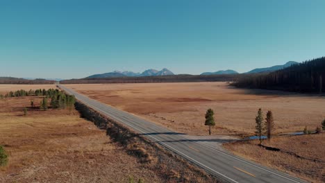 4K-Drone-fly-over-open-field-and-country-road-in-the-Sawtooth-Mountains,-Stanley-Idaho
