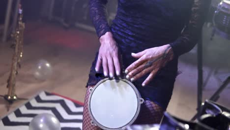 slow motion shot of a blonde talented musician playing a small drum during a concert with emotional gestures and facial expressions