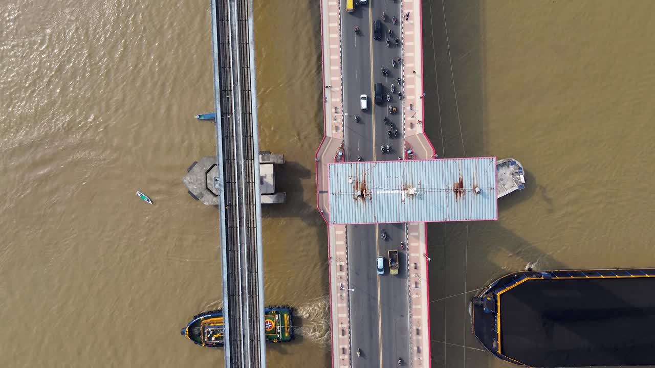 Drone aerial top view of a busy bridge crossing a wide river with cars motorcycles and boats Pollution mining Coal greenpeace Tugboat Crossing