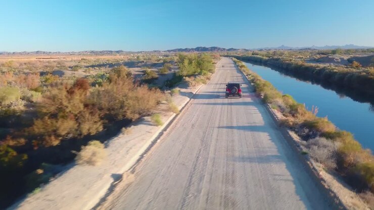vista aerea di seguire un suv che guida su strada vicino al canale di irrigazione a gravità di gila - yuma, arizona