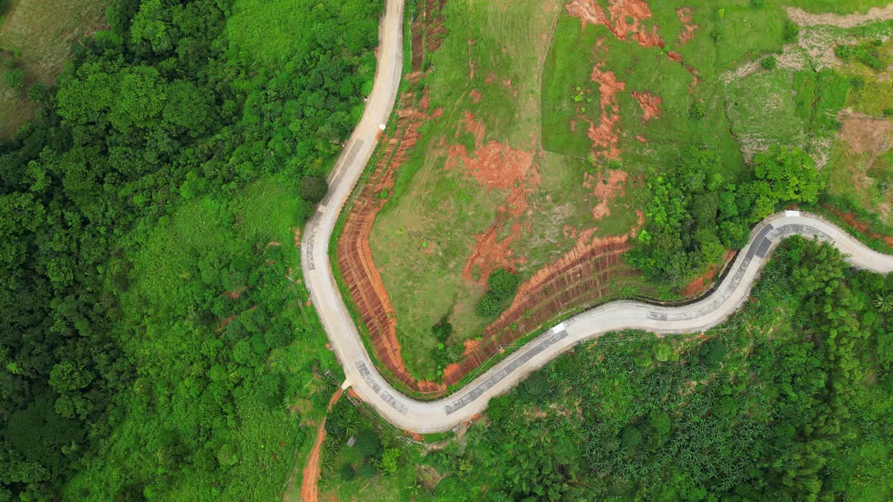 Slow rotating downward aerial of Quinawan Mountain View in Mariveles, Bataan, revealing winding roads, dense green trees, and rolling hills leading toward the coast