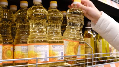 a young woman who picks up a bottle of olive oil in the supermarket. buying vegetable oil. slow motion