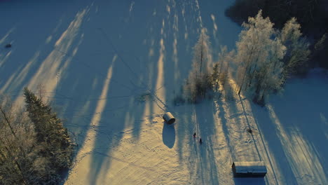 People-walk-in-snow-in-winter-in-rural-forest-environment-at-sunrise