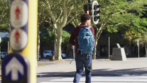 Hombre-Afroamericano-En-La-Ciudad,-Llevando-Mochila-Cruzando-La-Calle