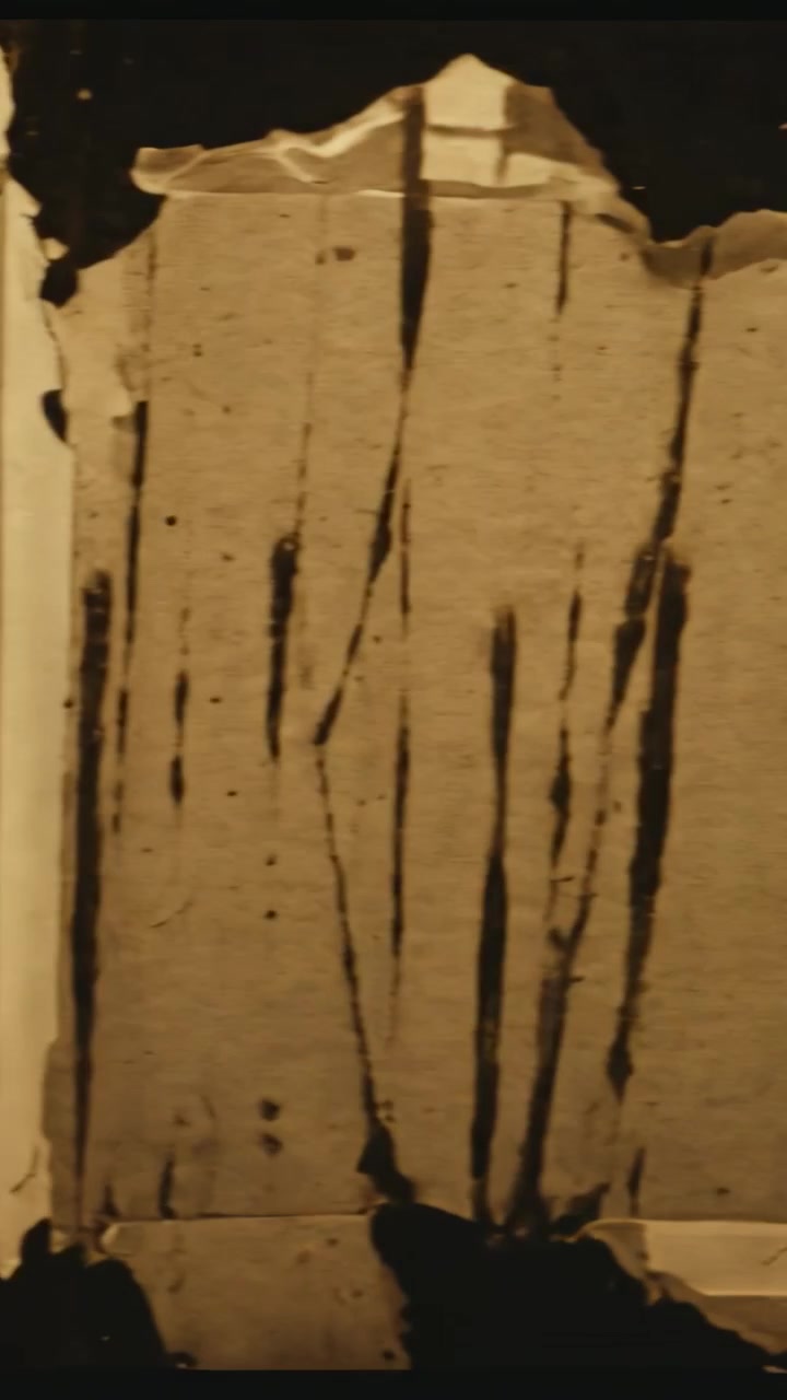 Video verticale: Panoramica della telecamera che rivela un pannello di carta beige strappato in primo piano per mostrare cuciture e macchie.