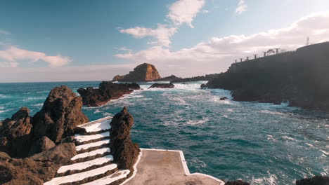 Walking-towards-waves-hitting-the-coast-of-sunny-Porto-Moniz,-Madeira---POV-shot