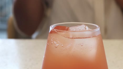 persona a punto de beber una bebida rosada