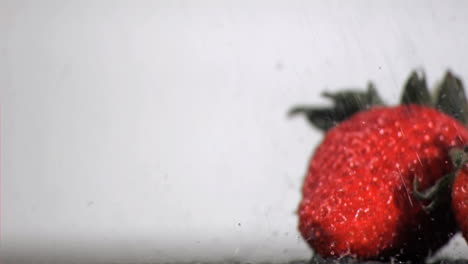 water in super slow motion falling on red fruits