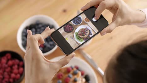 Woman-photographing-her-breakfast-in-kitchen