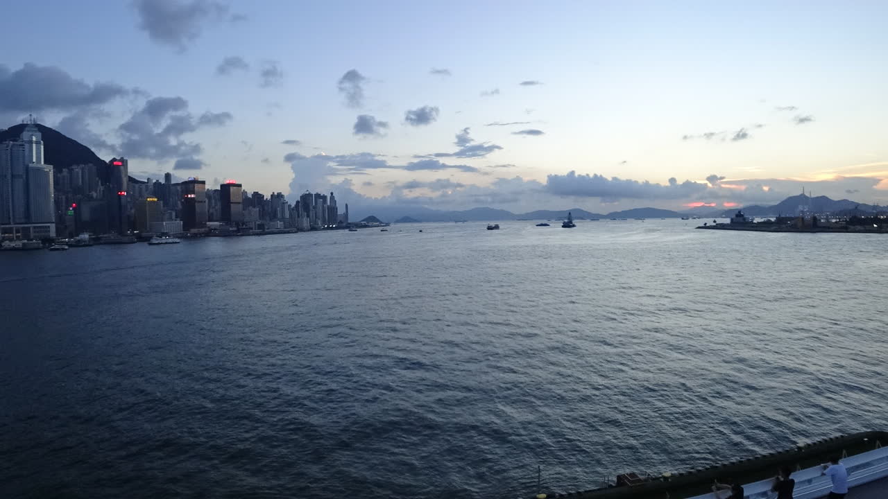 China,Hong Kong Harbor's time lapse during sunset, clouds and ships moving in and out, lights start to turn on one by one.