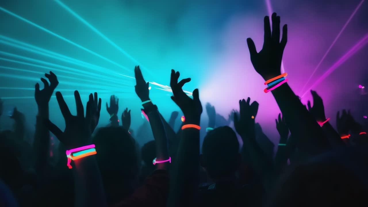 Crowd of people raising hands with glow sticks, reveling in live music, vibrant laser lights, and energetic dancing at an electronic music concert in a lively nightclub