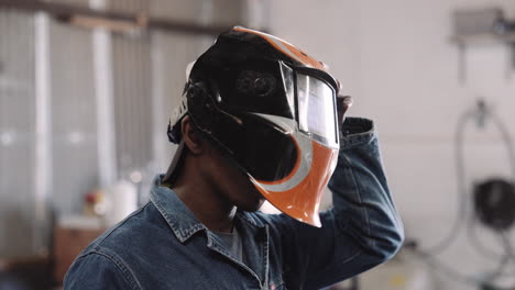 Slow-motion-close-up-young-black-male-putting-on-welding-helmet-mask