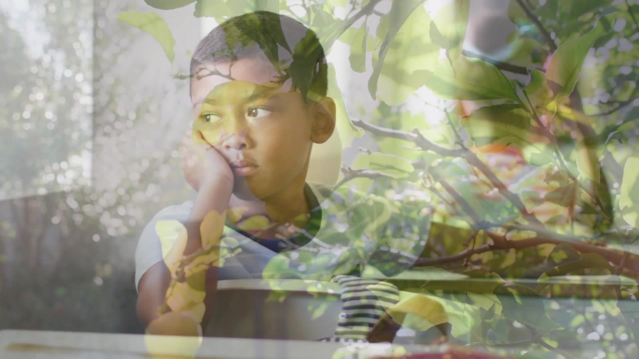 Boy resting cheek on hand at classroom desk, foliage overlay intensifying, causing gaze shifting