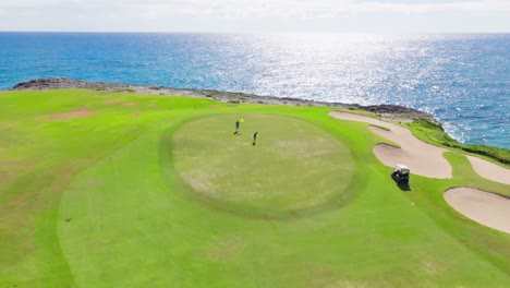 aerial arc around green with two golf players - corales golf course at puntacana