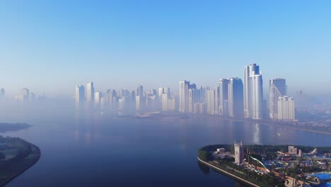 Vista-Desde-Arriba-Del-Lago-Khalid-De-Sharjah,-Horizonte-De-Sharjah-En-Una-Mañana-Nublada,-Niebla-En-El-Golfo,-Emiratos-árabes-Unidos,-Video-4k