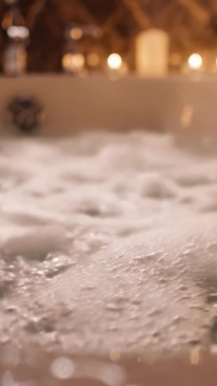 Una scena serena e invitante di una vasca da bagno con abbondanti bolle, illuminazione soffusa e un'atmosfera rilassante, perfetta per un'esperienza spa rigenerante a casa