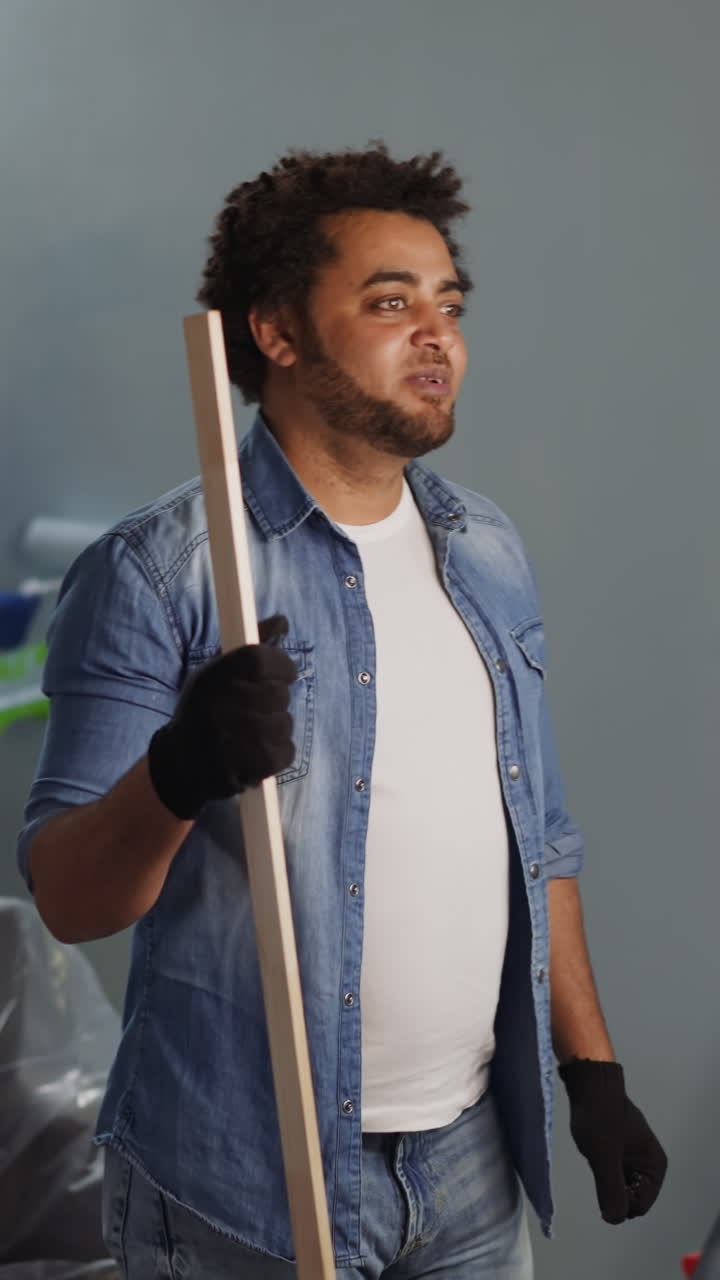 African-American man blogger shoots video while colleague applies paint on wall in studio. Black constructors teach audience to do domestic repair