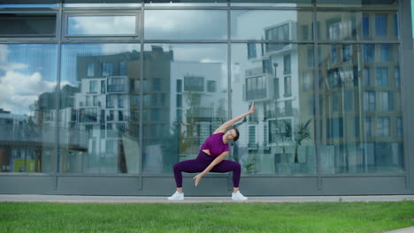 woman doing yoga poses outdoors in front of a modern building