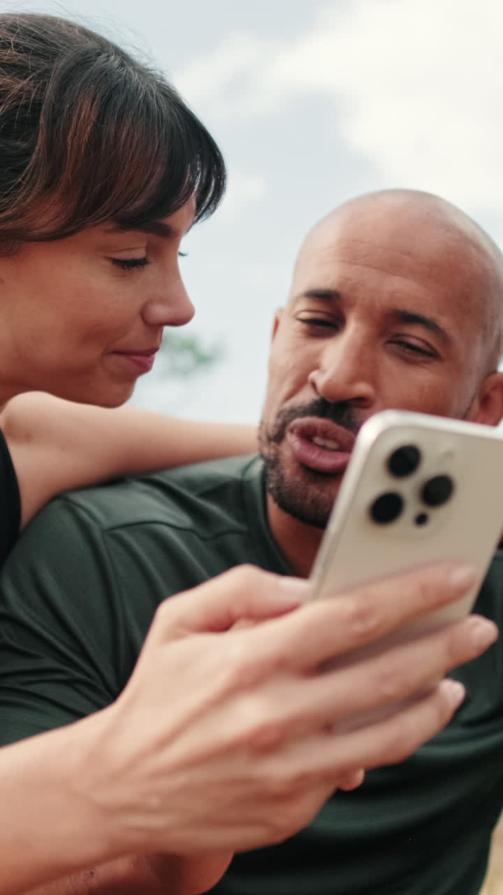 Casal Conversando e Sorrindo Olhando um Smartphone ao Ar Livre