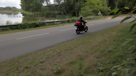 man driving past beautiful lake in ardeche on his beautiful motorcycle