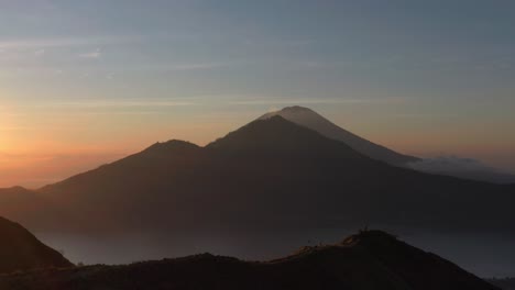 tourist standing on mount batur ridge during magical morning sunrise in bali, aerial