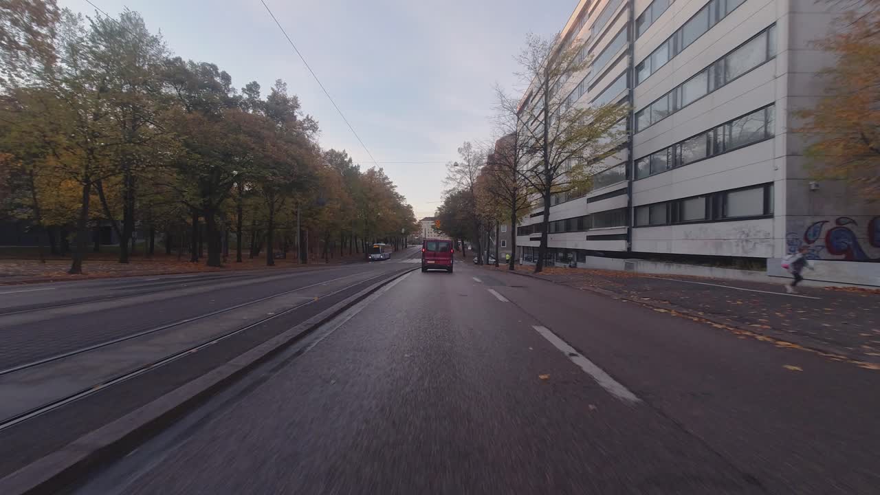 Fahrerperspektive: Nasse Straßen und Herbstfarben bei morgendlicher Stadtfahrt.