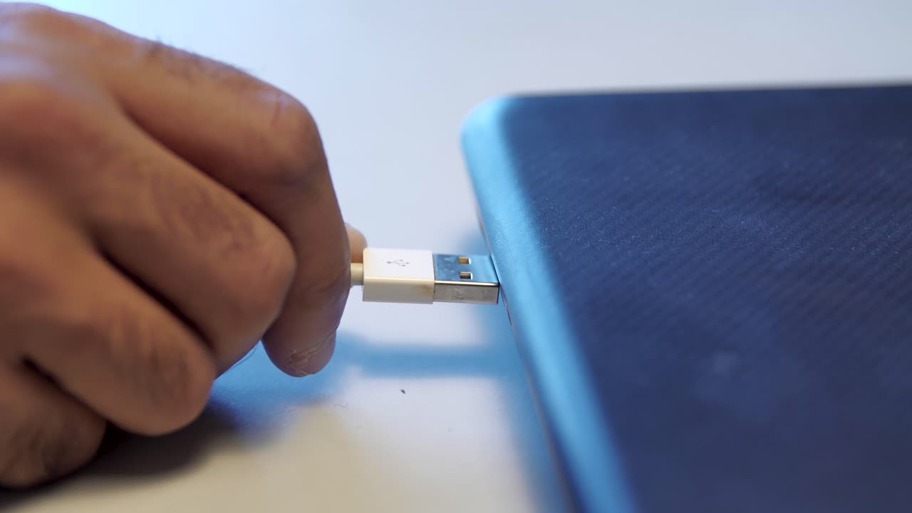 conectando a mano un cable usb a una computadora portátil