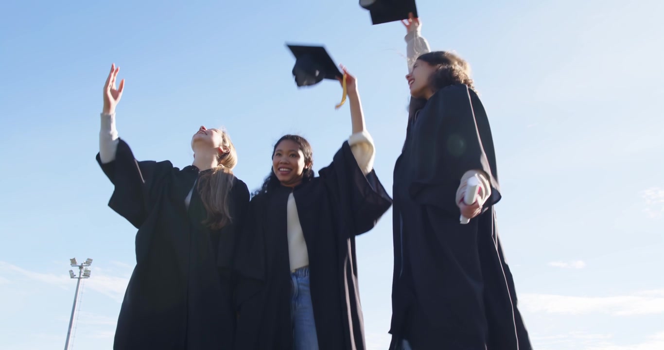Diverse Laureate in Posa nel Campus con Toga e Lancio dei Cappelli dopo che la Leader Solleva il Cappello
