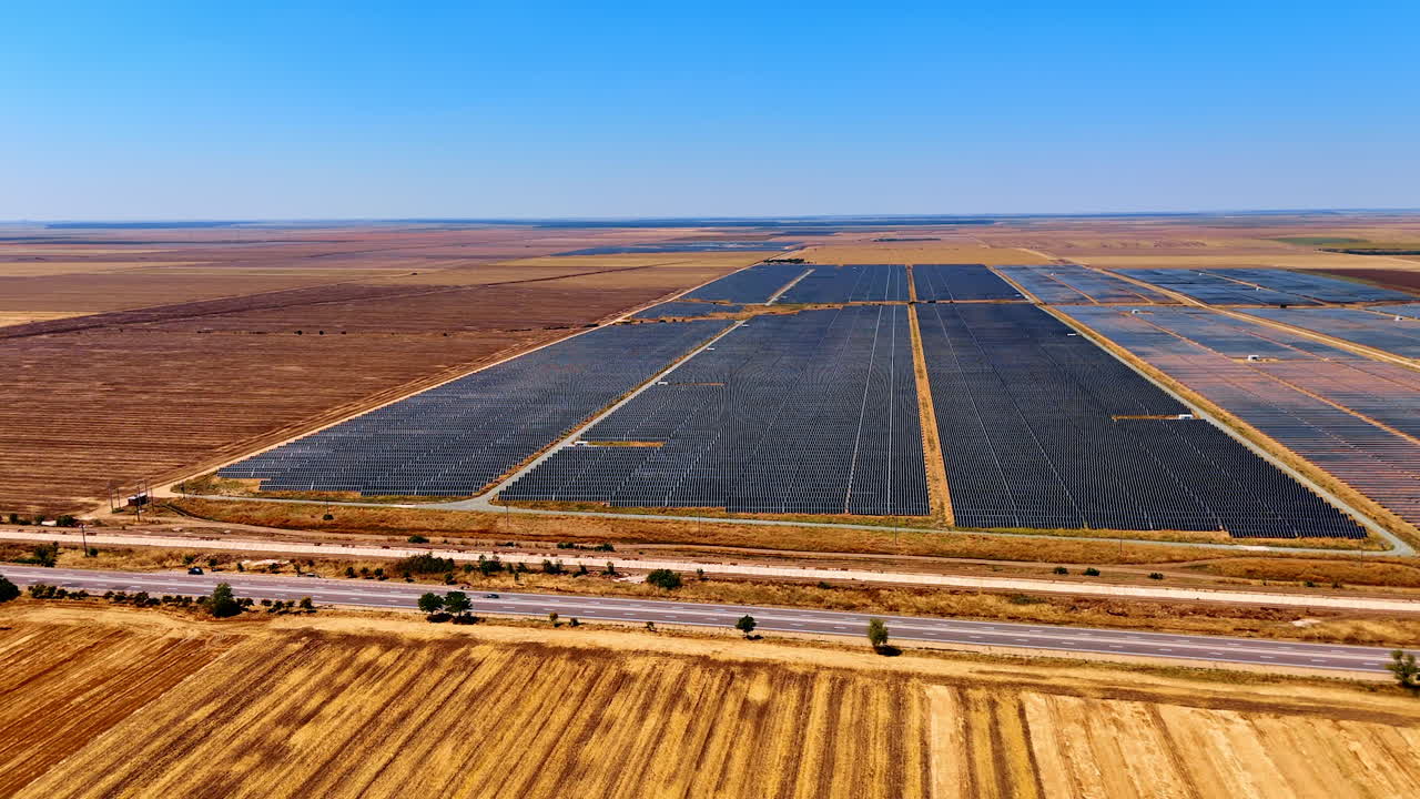 Large solar farm in countryside. Rows of solar panels stretch across the land under a clear blue sky, showcasing renewable energy in a rural setting
