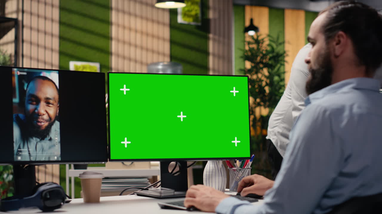 Mand arbejder ved computer med grøn skærm og videoopkald
