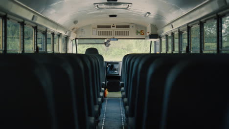 empty aisle black seats in schoolbus. bus interior without passengers close up.