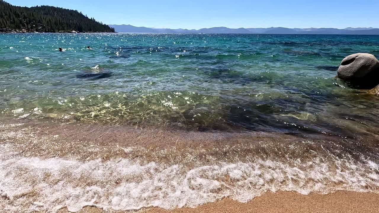 네바다 주 카슨시티에 있는 타호 호수 동쪽 해변에 있는 비밀 항구 해변의 은 푸른 물에서 수영하는 사람들.