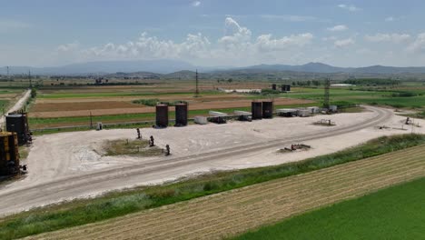 aerial shot of large oil deposit tanks situated in the middle of a farming field causing pollution