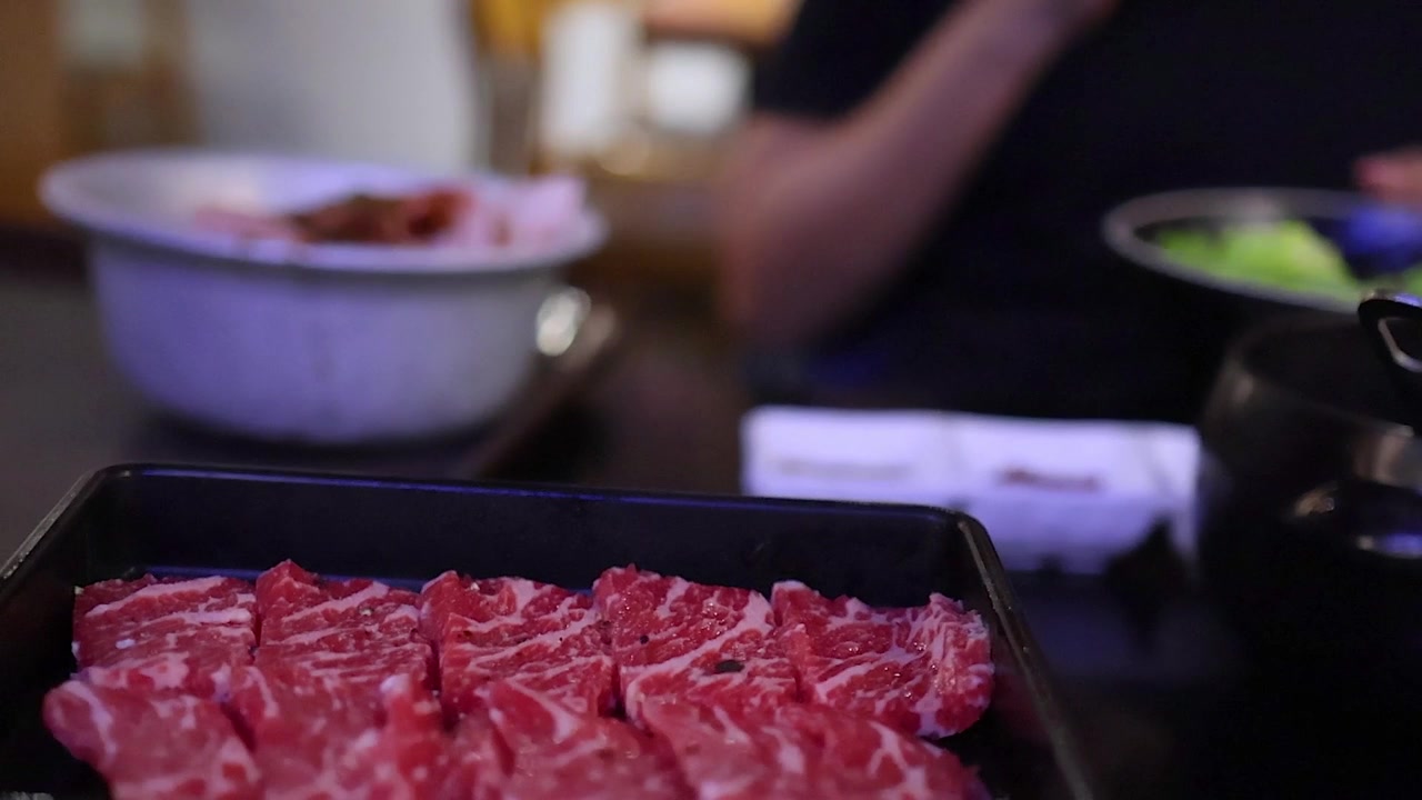 Un primo piano di fette di manzo crudo marmorizzato servite su un vassoio nero.
