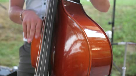 Primer-Plano-Del-Hombre-Tocando-El-Contrabajo-Con-Los-Dedos-Al-Aire-Libre,-Cámara-Lenta