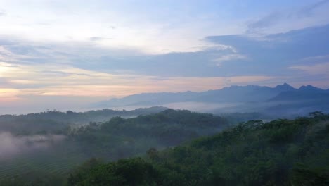 Mysterious-drone-flight-over-lush-green-hills-and-mountains-during-foggy-day-at-sunset