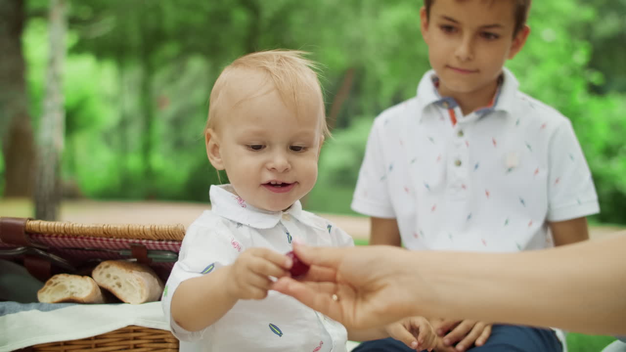 Madre con i figli seduti su una coperta al parco. Famiglia che trascorre il weekend insieme.