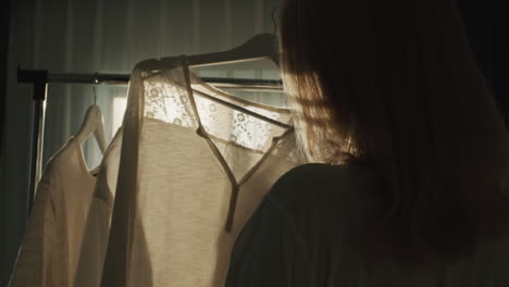 a woman chooses clothes in the dressing room. silhouette in the sun, rear view