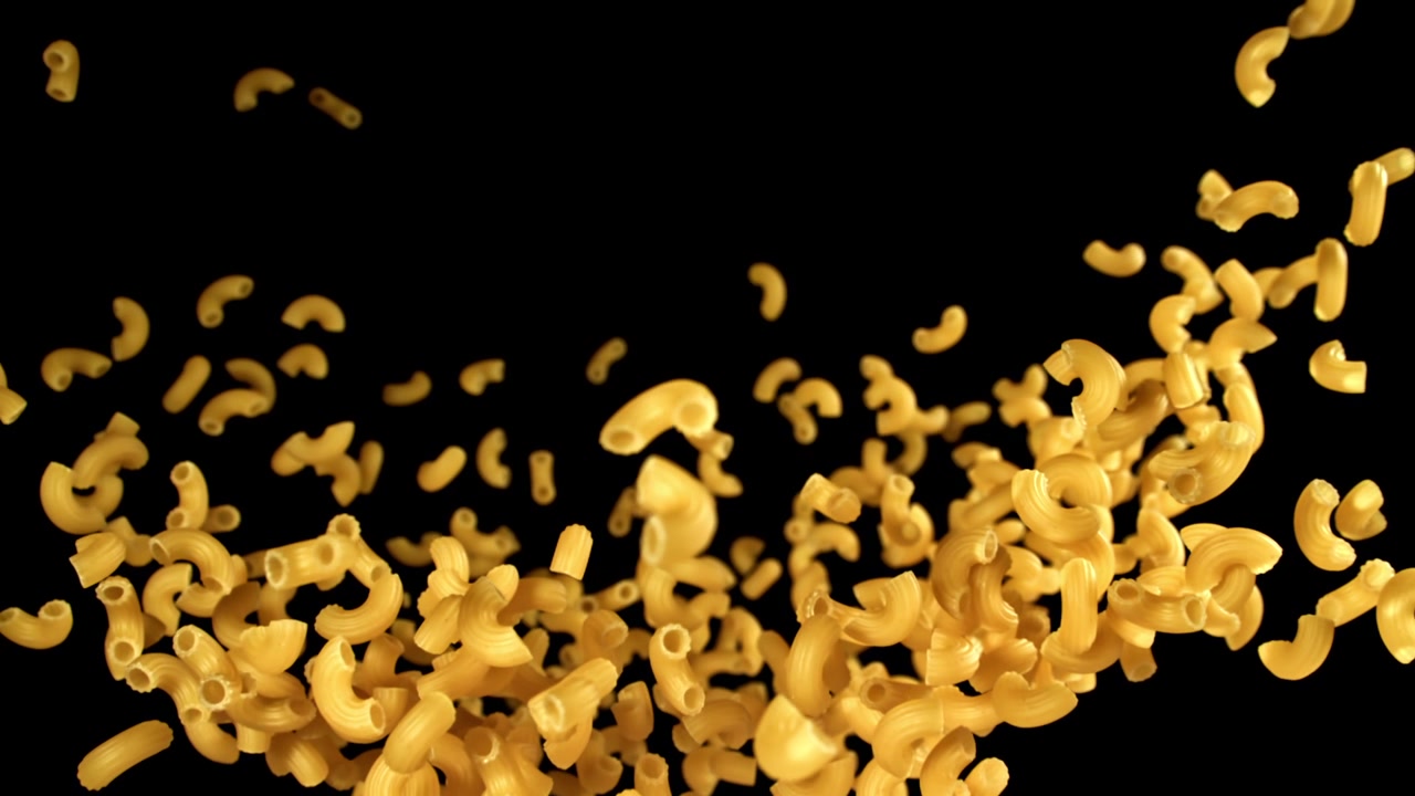 Maccheroni crudi che cadono su sfondo nero al rallentatore