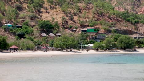 Casas-Timorenses-Tradicionales-En-Las-Colinas-Y-Niños-Jugando-En-El-Mar-En-La-Impresionante-Playa-De-Arena-Blanca-Costa-De-La-Isla-Tropical-En-Dili,-Timor-Leste,-Sudeste-De-Asia