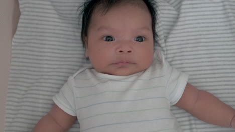 portrait of an adorable baby in fabric mesh crib looking at the camera