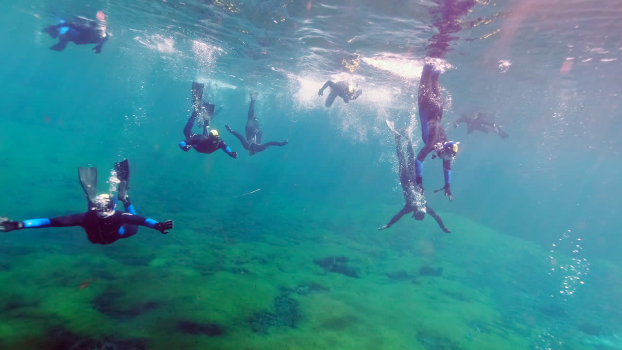 Group of snorkeler diving in the crystal clear Ewens Pond during sunlight.Sun reflection on water surface.Exploring underwater world.