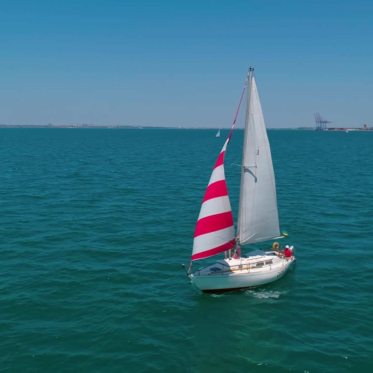 Beautiful boat with sails on water. Yacht sailing in sea on the coastline background. Sailboat floating