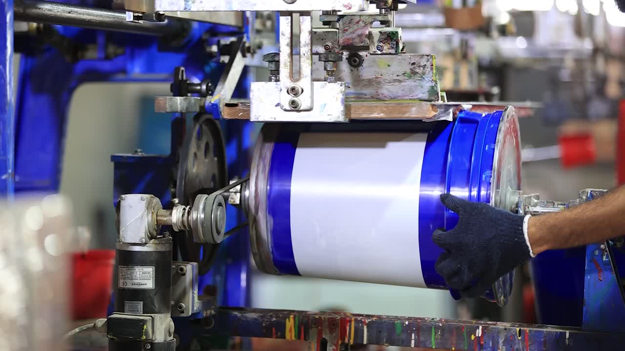 Mid close up shot of big can in automatic sticker machine in factory, industry 5.0