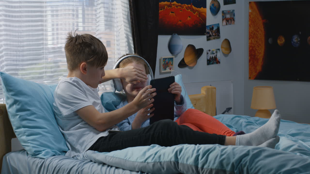 Children Using Tablet and Headphones in Bedroom
