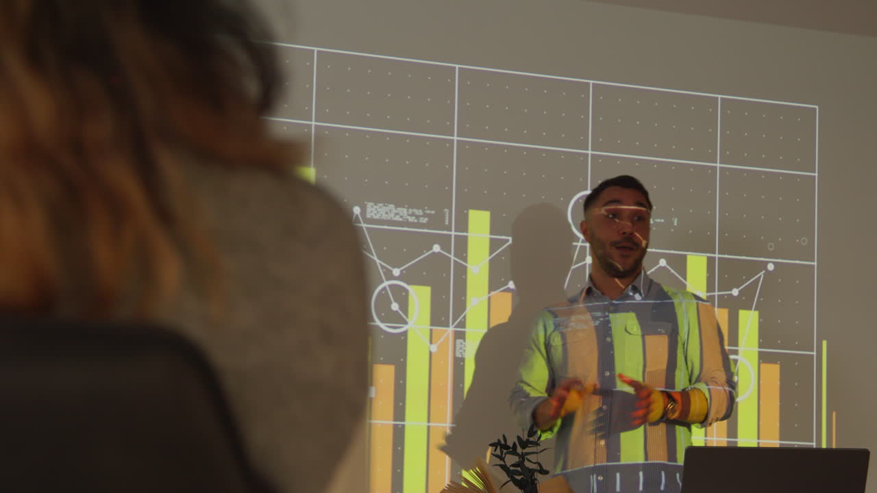 profesor masculino dando lecciones de matemáticas o ciencias en una universidad o universidad de pie en la parte delantera de la clase con una proyección de gráfico