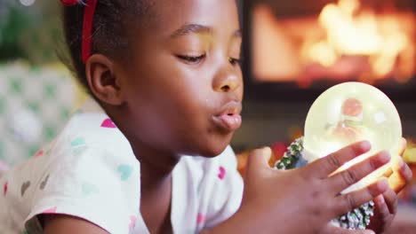 Glückliches-Afroamerikanisches-Mädchen,-Das-Mit-Einer-Schneekugel-Spielt