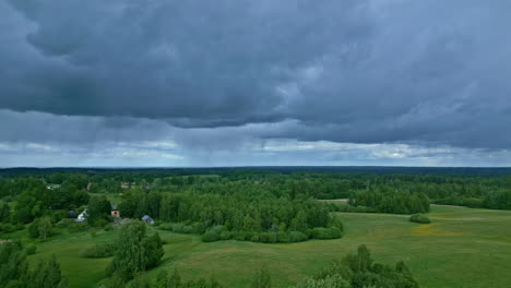 ominous dark blue clouds slowly moving over lush green fields with trees below in a dramatic landscape